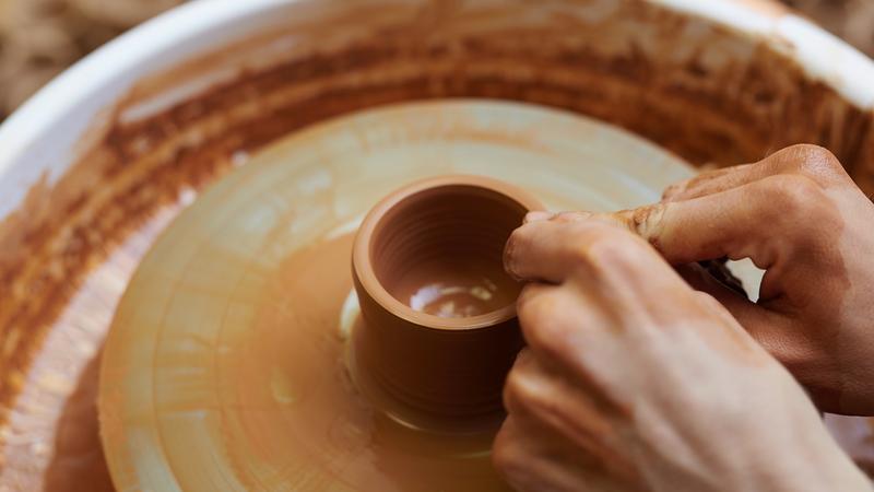 Image of mud being caved into a pot on potters wheel representing craftsmanship